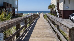 A wooden boardwalk leading to a beach with a building on the right. - "Sunshine At The Beach - Fall Specials! Many Upgrades! Perfect Location! (Orange Beach)