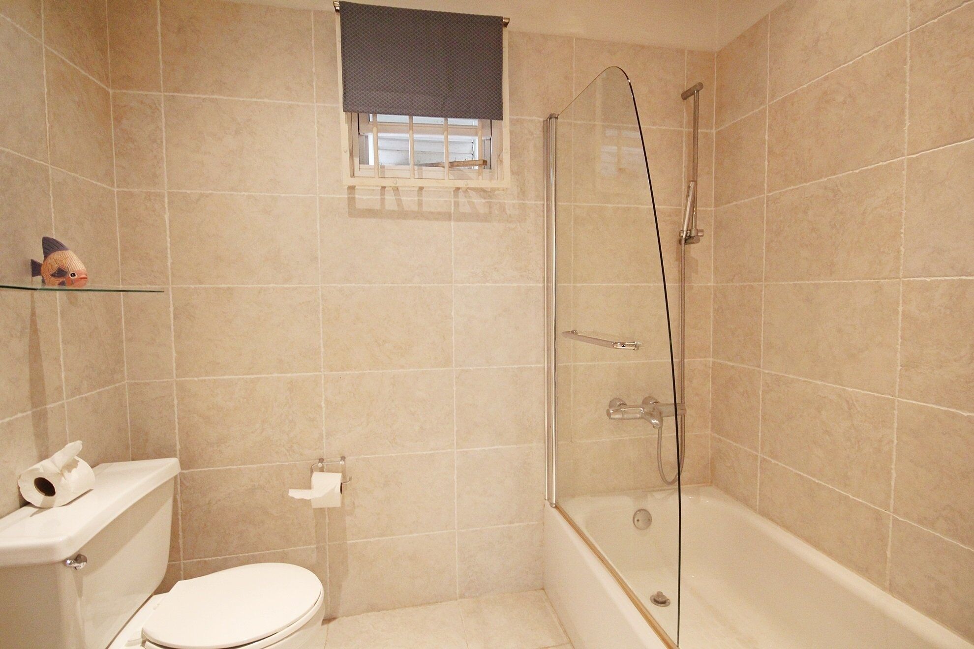 Une salle de bain avec des toilettes, une douche et une petite fenêtre.
