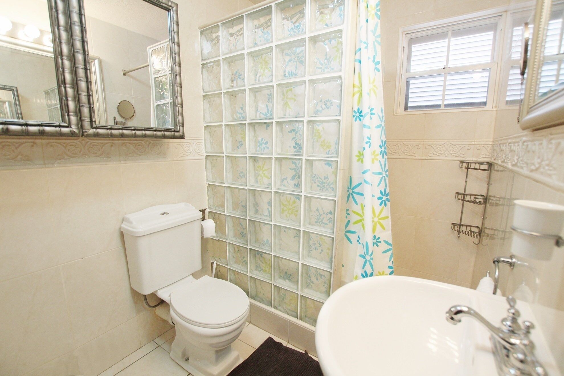 Une salle de bain comprenant des toilettes, une douche à parois de verre, un lavabo et un miroir.