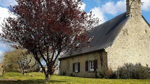 A stone building with a steep roof and a chimney, surrounded by grass and trees. - Normandieheritage14 Cottage du Marais Omaha Beach D-Day Tour Guide E-bike Hiking (Canchy)