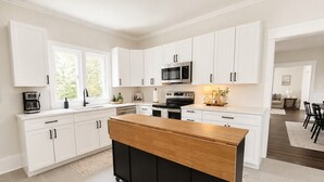 Une cuisine moderne avec des meubles blancs, un îlot central et un four à micro-ondes placé au-dessus de la cuisinière.