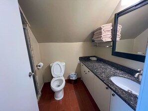 Un baño con inodoro, lavabo y toallas apiladas.
