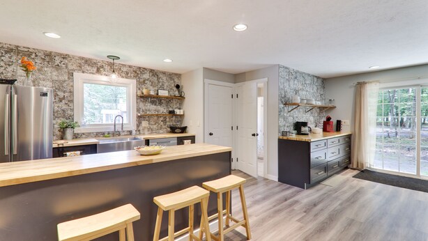 A modern kitchen with a central island, bar stools, and built-in appliances. - Large home & 5 min to Kalahari, Gather here at WOODLAND RETREAT! (Pocono Summit)