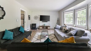 A modern living room with a sofa, armchairs, a coffee table, and a TV. - Large home & 5 min to Kalahari, Gather here at WOODLAND RETREAT! (Pocono Summit)