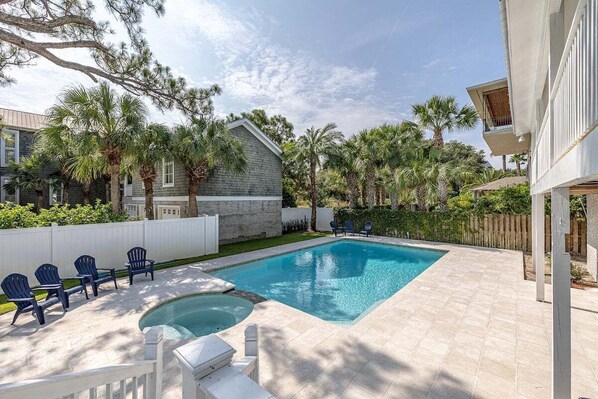 A rectangular swimming pool with a hot tub, surrounded by a patio with chairs and a wooden fence. - 4203 10th Street - East Beach (Saint Simons Island)