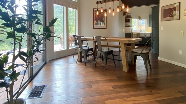 Un comedor amplio con una gran mesa de madera y sillas, ventanas grandes y una lámpara colgante.