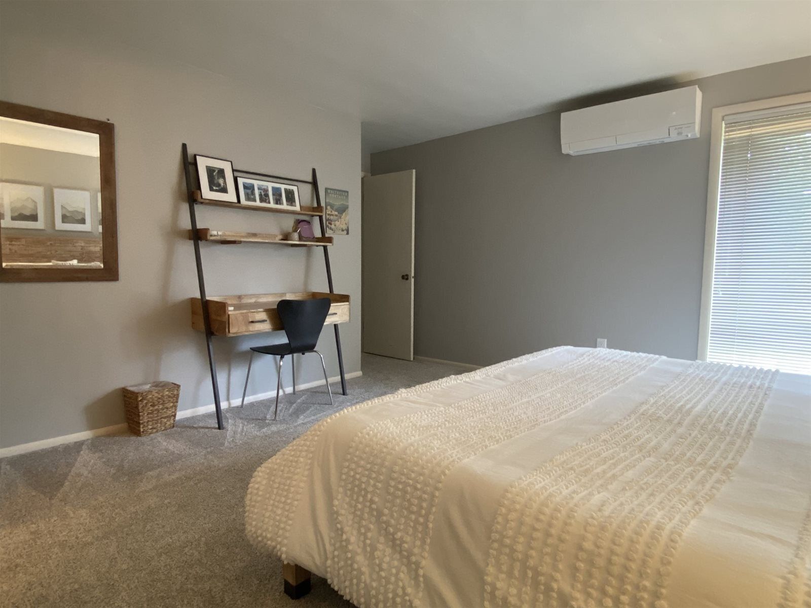 A bedroom with a bed, a desk, and a chair.