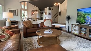 Una sala de estar moderna con un sofá de cuero, una mesa de centro redonda y un televisor de pantalla plana.