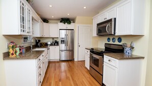 A kitchen with white cabinets, a stainless steel refrigerator, a microwave, and an oven. - Cozy Cottage with view of Lake Michigan (St. Joseph)