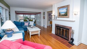 A cozy living room with a fireplace, a blue sofa, a red armchair, and a coffee table. - Cozy Cottage with view of Lake Michigan (St. Joseph)