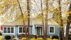 A house with a front porch, stone steps, and a small garden with yellow flowers. - Cozy Cottage with view of Lake Michigan (St. Joseph)