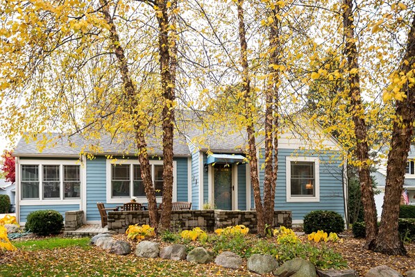 A house with a front porch, stone steps, and a small garden with yellow flowers. - Cozy Cottage with view of Lake Michigan (St. Joseph)