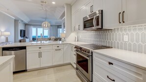 Uma cozinha moderna com armários brancos, eletrodomésticos de aço inoxidável e um backsplash estampado.