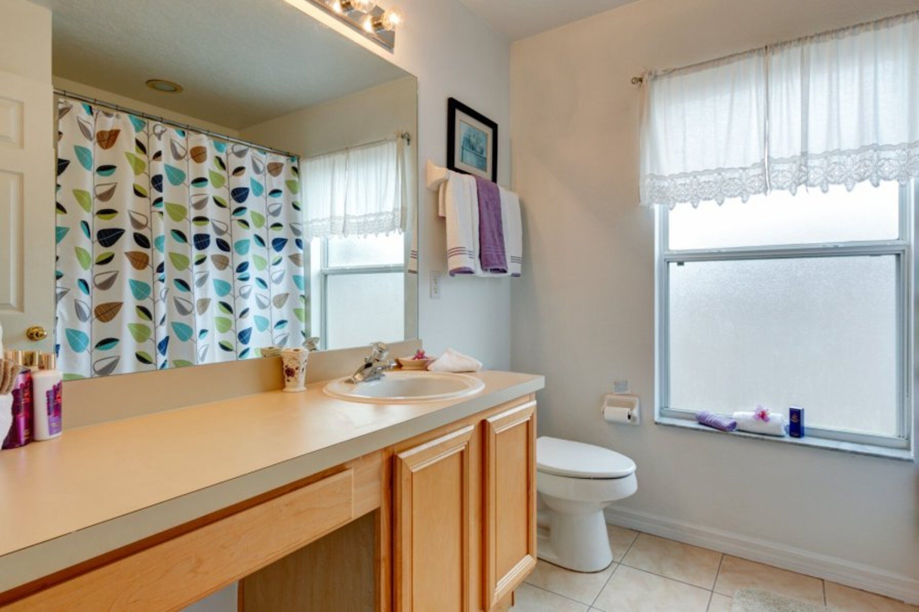 A bathroom with a wooden vanity, a white sink, a mirror, and a toilet.