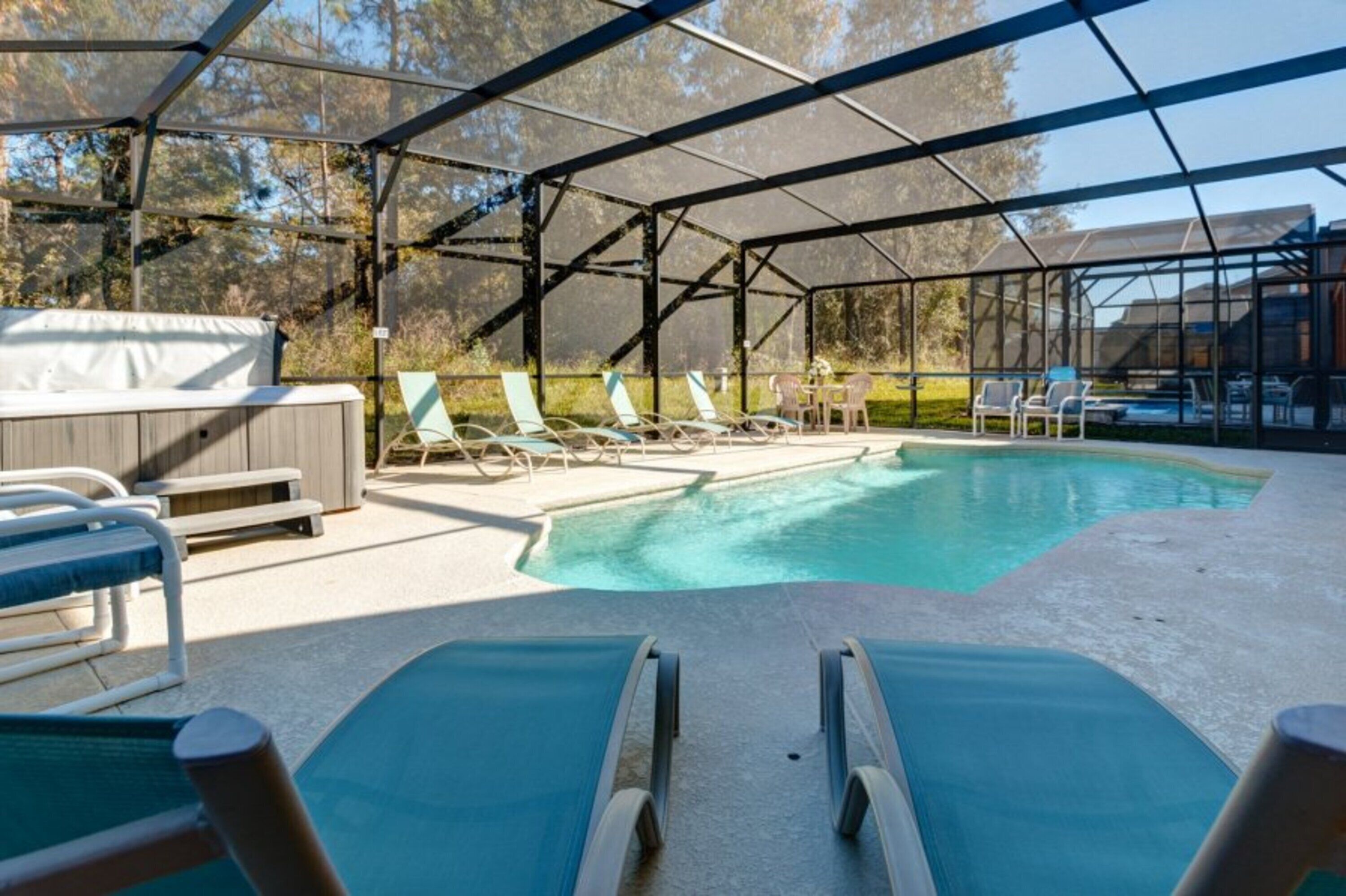 Una piscina exterior techada con sillas de descanso y un jacuzzi.