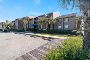 A modern hotel with multiple buildings, a covered walkway, and palm trees.