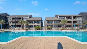 Ein modernes Hotel mit großem Pool, mehreren Balkonen und Sitzgelegenheiten im Freien.