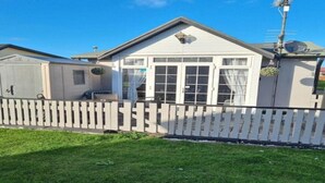 Une maison de plain-pied à l’extérieur blanc, dotée d’un porche à l’avant et d’une cour arrière clôturée.