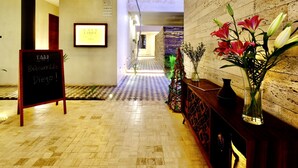 A hotel lobby with a checkered floor, a welcome sign, a framed picture, and a vase with flowers. - 406 Awesome 1Br 2pax designer condo (Playa del Carmen)