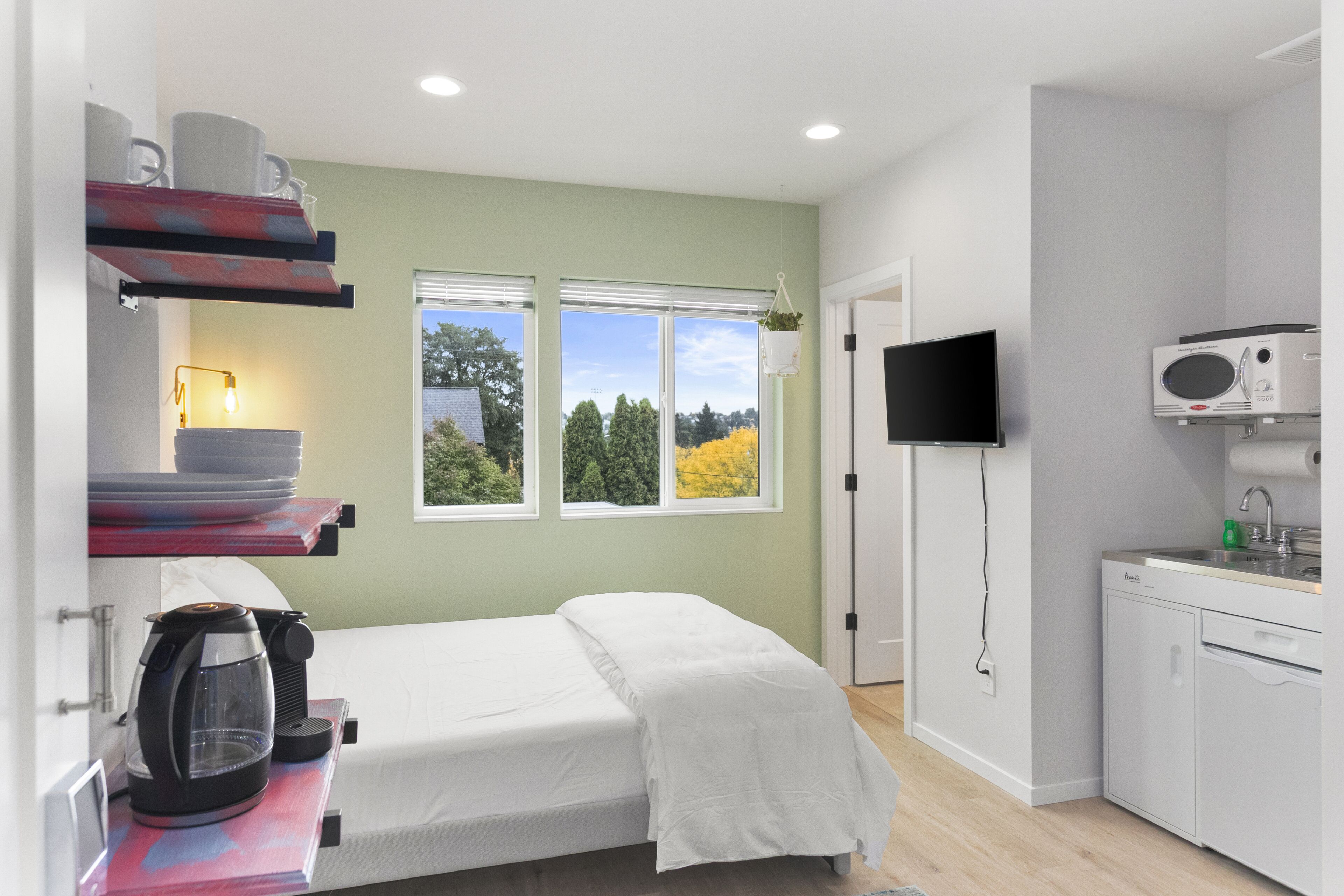 Ein gemütliches Schlafzimmer mit Bett, Kaffeemaschine und Fernseher.