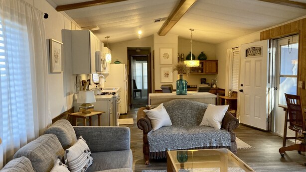 A spacious living room with a sofa, a coffee table, and a dining area with a kitchen in the background. - Convenient NE Albuquerque location, right off I-25!! (Albuquerque)