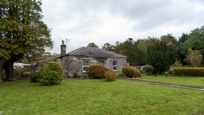 A stone house with a well-maintained lawn and mature trees. - Beautiful 200 year old Cottage near St Andrews (Markinch)