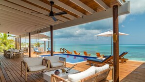 A wooden deck with a pool, lounge chairs, and a view of the ocean. - IslandChicBeachFrontHome!StunningViews-Pool,OutdoorKitchen,Reef,Mini BballCourt (Rokers Point Settlement)