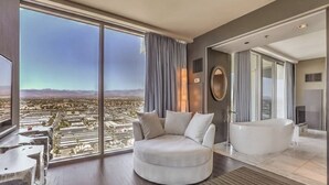 A modern hotel room with a large window offering a city view, a round white sofa, a large bathtub, and a minimalist decor style. - Immaculate Views in Las Vegas High Rise Corner Unit  (Las Vegas)