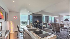 A modern hotel room with a kitchen area, a dining table, and a seating area with a view of the city. - Immaculate Views in Las Vegas High Rise Corner Unit  (Las Vegas)