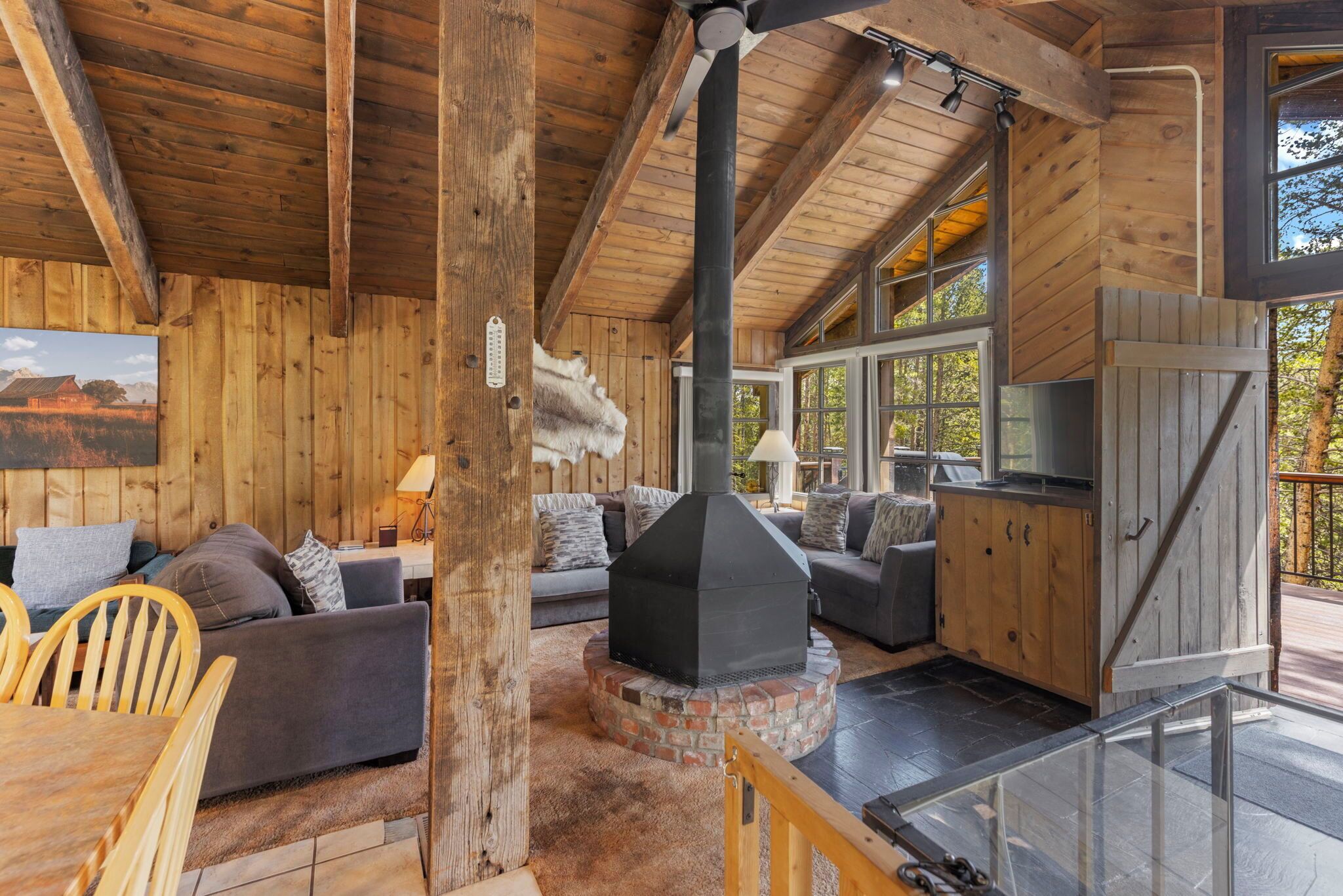 A rustic cabin interior with a fireplace, wooden walls, and a dining area.