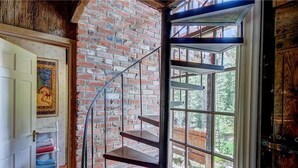 A staircase with a metal railing against a brick wall, leading to a large window with a view of greenery outside. - Brecken Haus (Breckenridge)