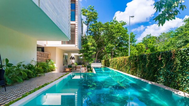 A swimming pool with a checkered floor, surrounded by greenery and a modern building. - 404 Awesome 1Br designer by StayPodio (Tulum)