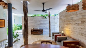 A modern interior with a dining area, wooden walls, and a ceiling fan. - 404 Awesome 1Br designer by StayPodio (Tulum)
