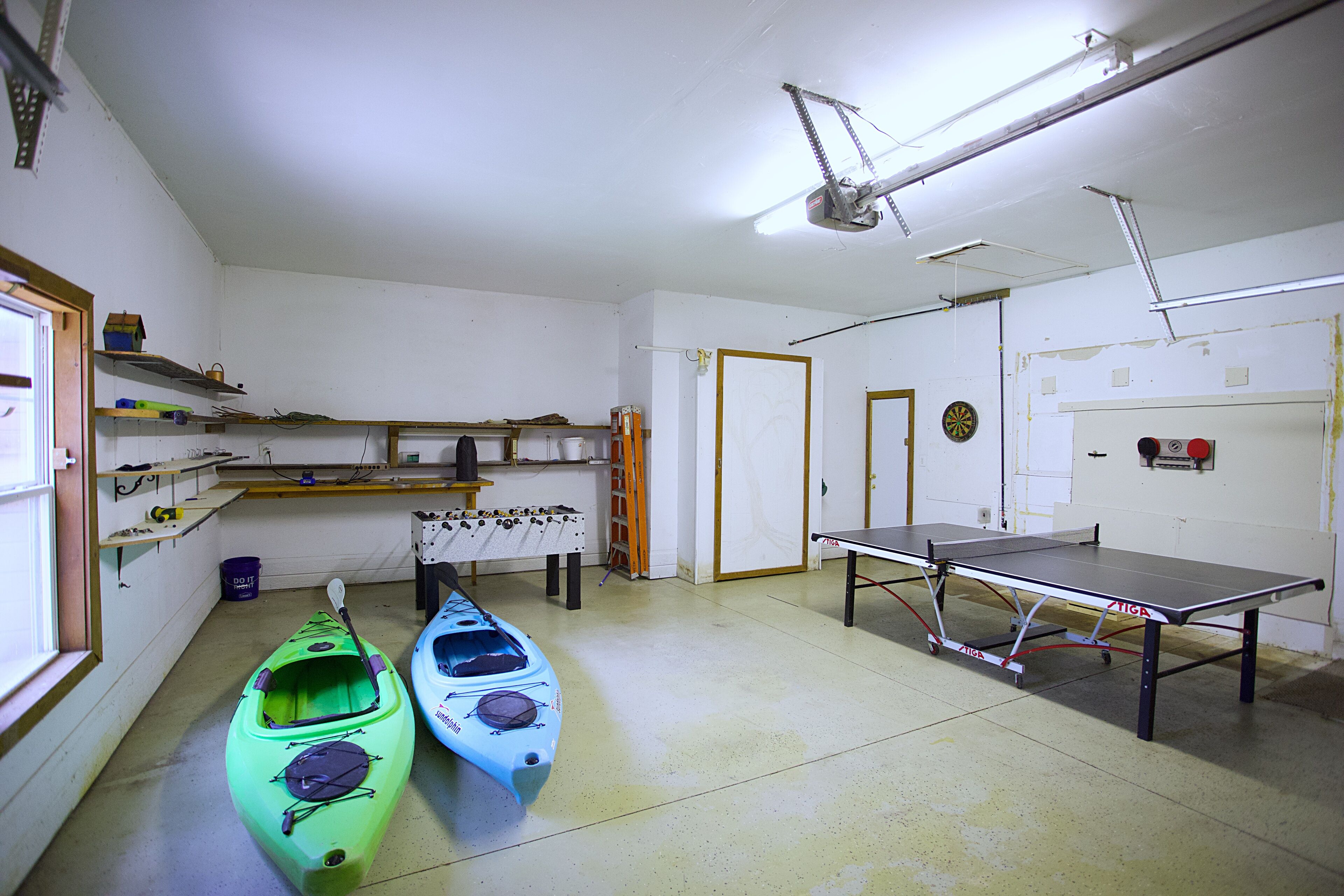 Habitación con kayaks, mesa de ping pong y estantes con diversos objetos.
