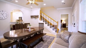 A dining area with a wooden table and chairs, a ceiling fan, and a clock on the wall.