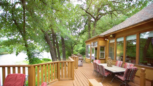 A wooden deck with a table and chairs, overlooking a body of water.