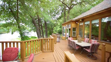 A wooden deck with a table and chairs, overlooking a body of water.