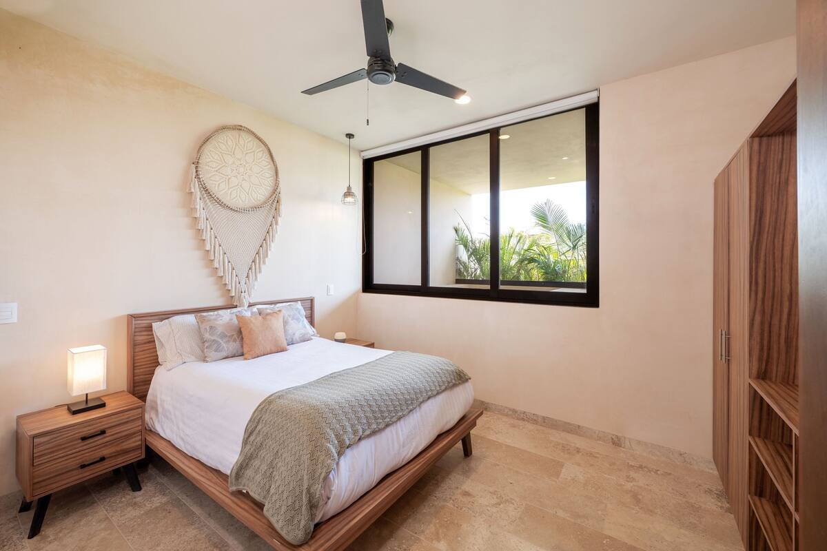 A bedroom with a bed, bedside table, wall decor, and a window with a view.