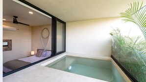 A modern room with a glass-enclosed hot tub, a bed with a patterned blanket, and a ceiling fan. - Two Bedroom Luxury Apartment by TuLuna (Tulum)