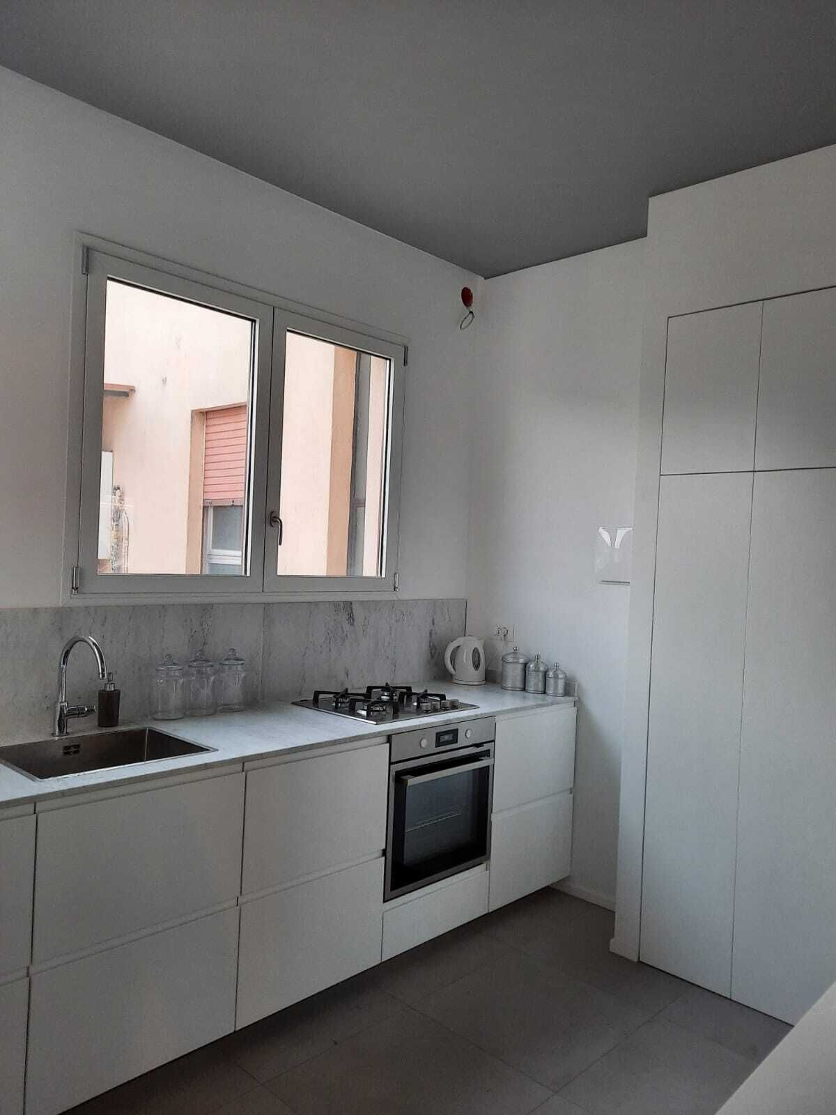 Een moderne keuken met een gasfornuis, oven en een groot raam.