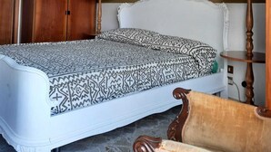 Un dormitorio con una cama grande, un armario de madera y una araña.