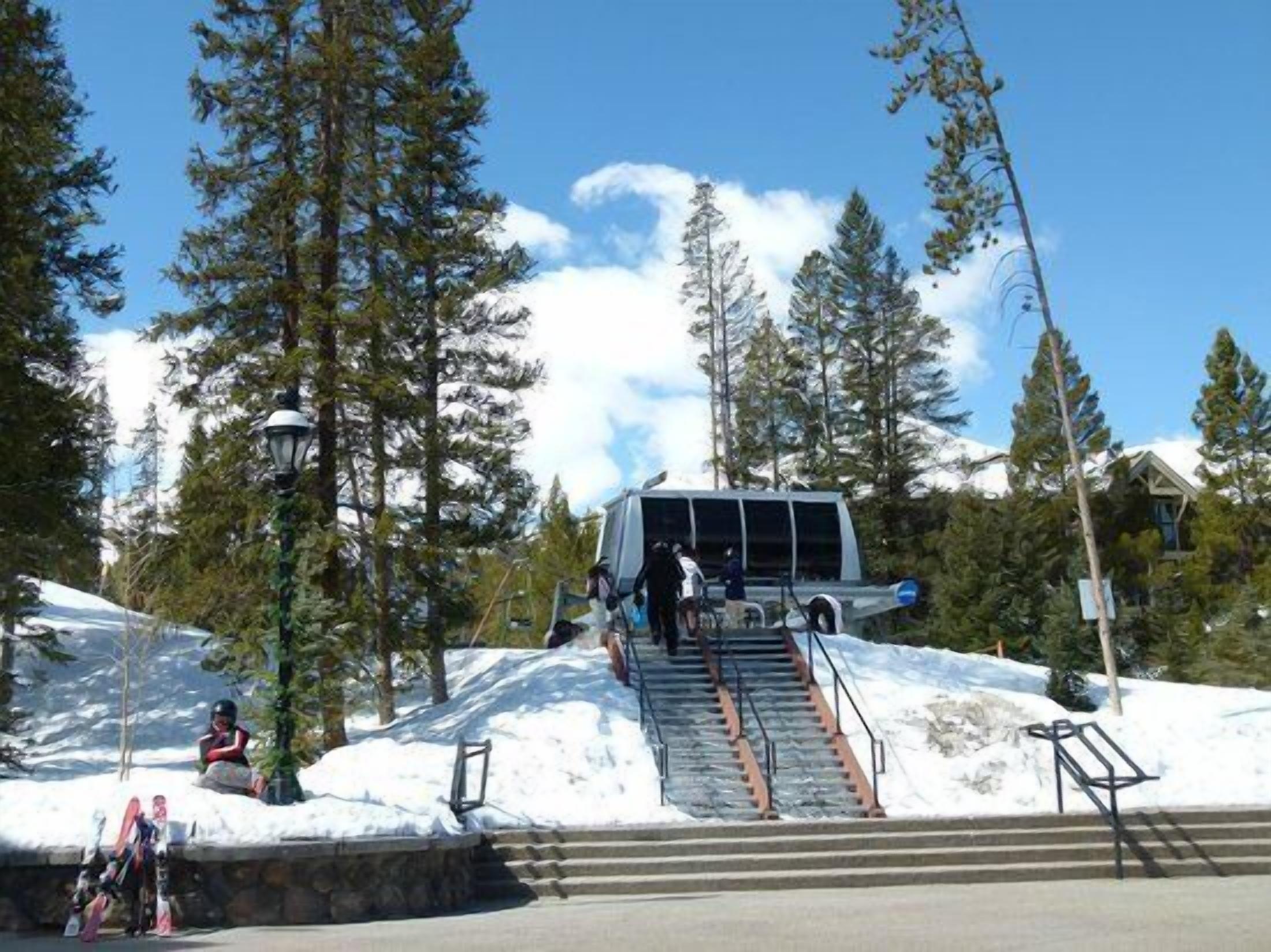 A ski lift station with a chairlift, surrounded by snow-covered slopes and tall evergreen trees.