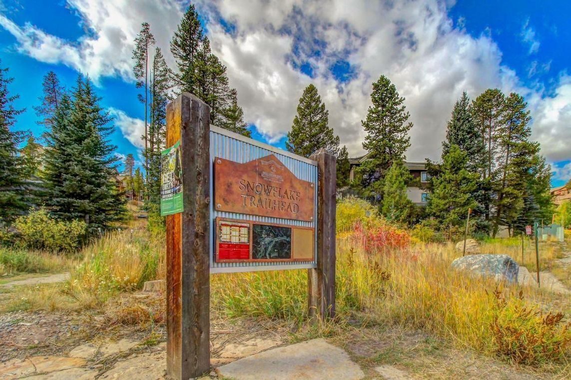 A sign for Snow Lake Trailhead surrounded by trees and a clear sky.