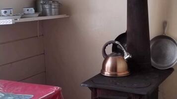 A kitchen with a stove, kettle, pots, and a red tablecloth.