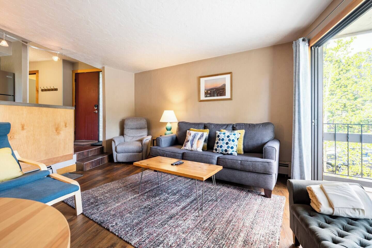 Un salon moderne avec un canapé gris, une table basse en bois et un fauteuil bleu.
