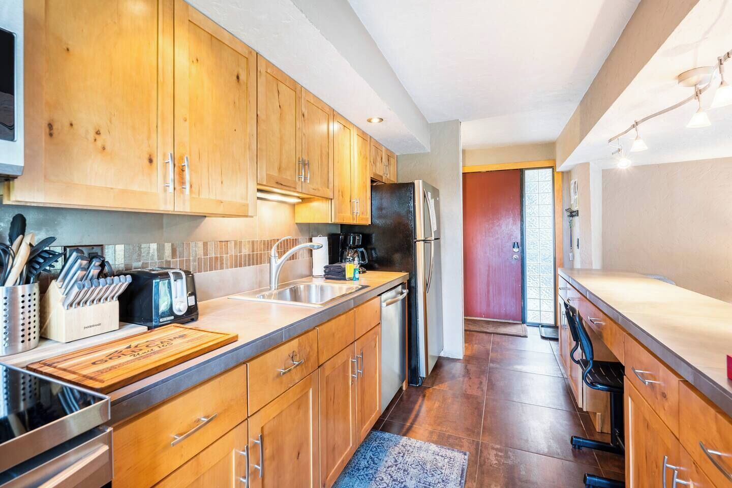 A modern kitchen with wooden cabinets, stainless steel appliances, and a large island.