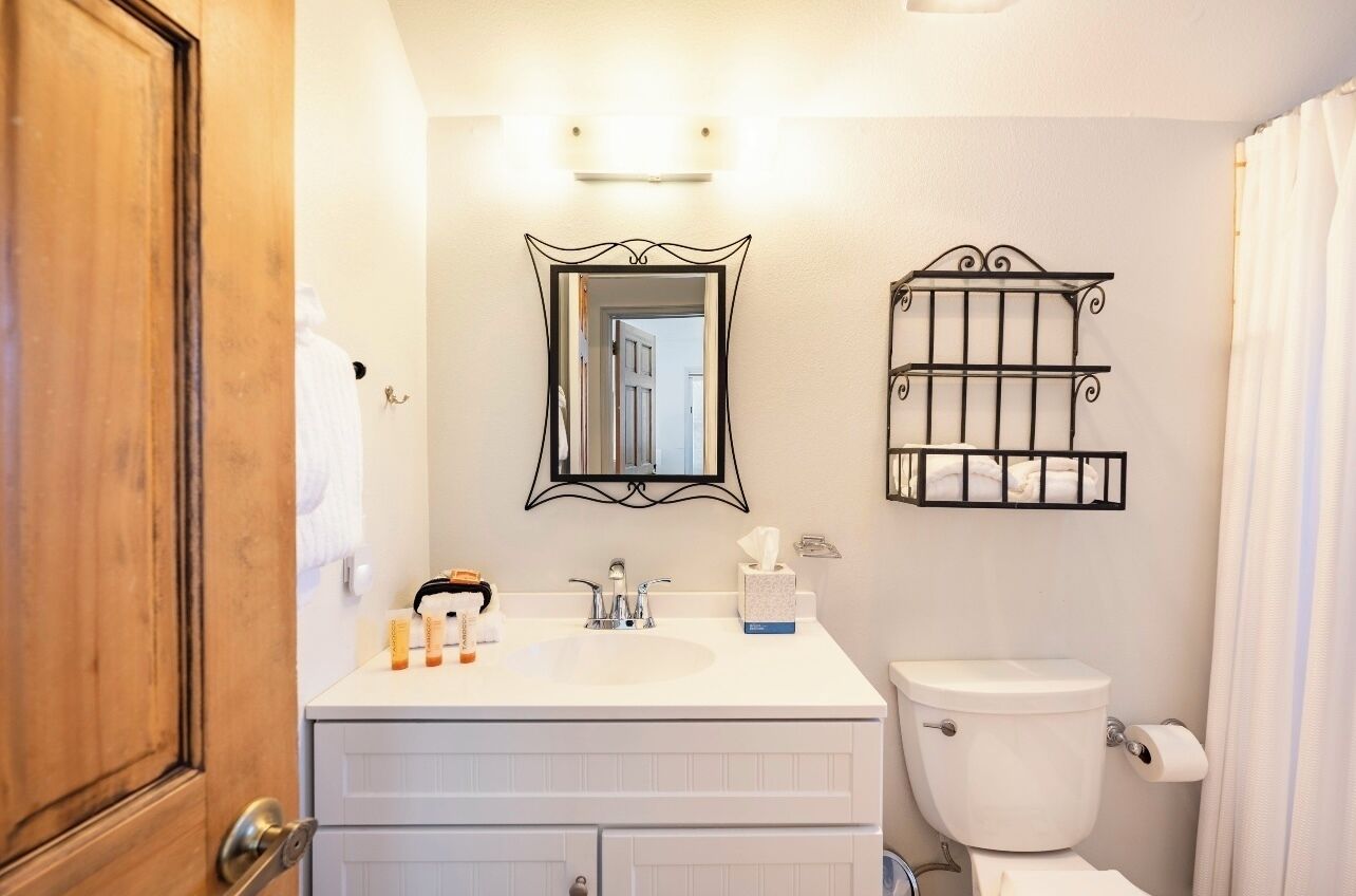 A bathroom with a white sink, a mirror, a toilet, and a towel rack.