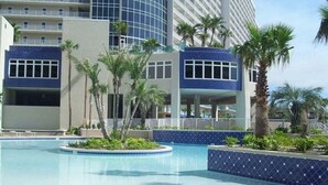 Una piscina circondata da palme e un edificio moderno con facciata in piastrelle blu.