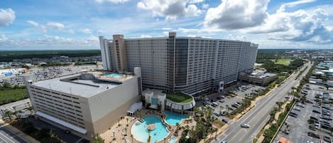 A large hotel with multiple floors, a rooftop pool, and a parking area.