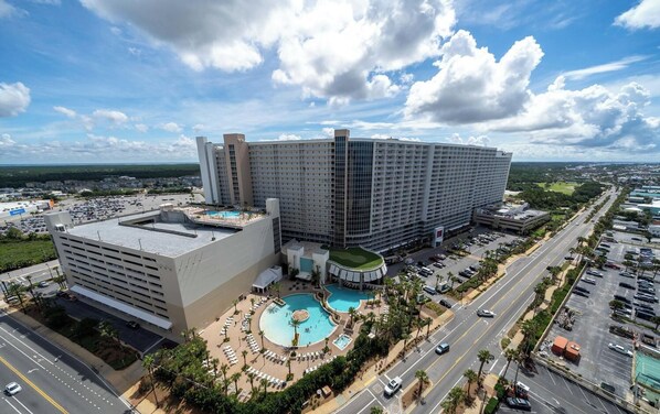 A large hotel with multiple floors, a rooftop pool, and a parking area.